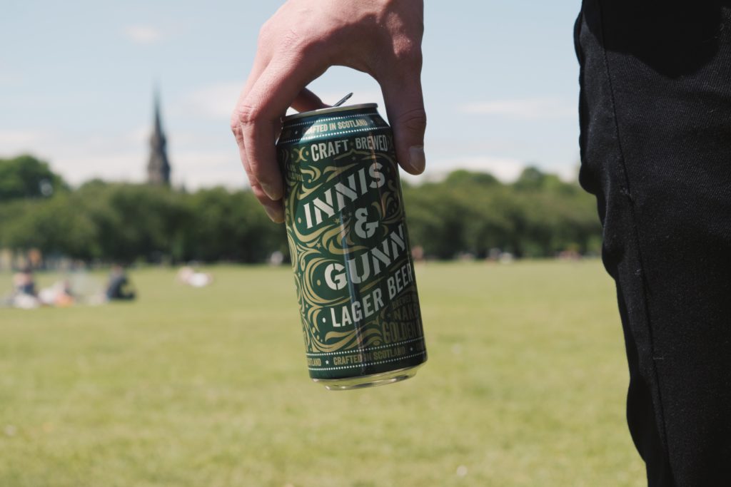 man holding can of beer in park