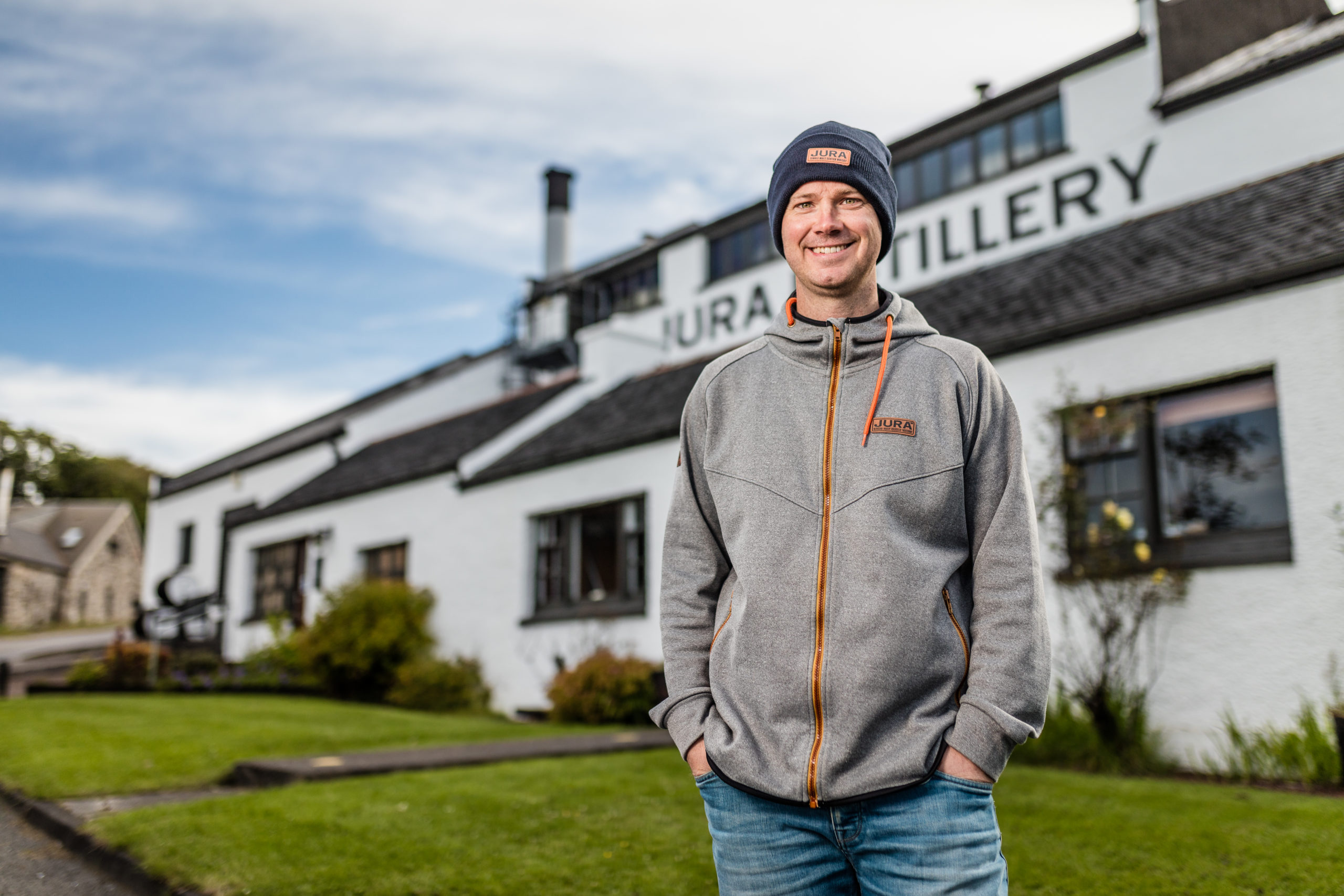 man smiling in front of distillery